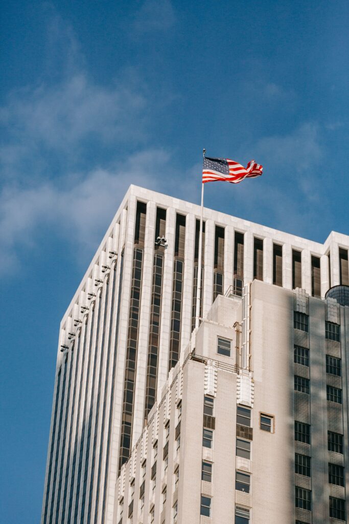 Low angle of modern high multistory tower with waving American flag on top